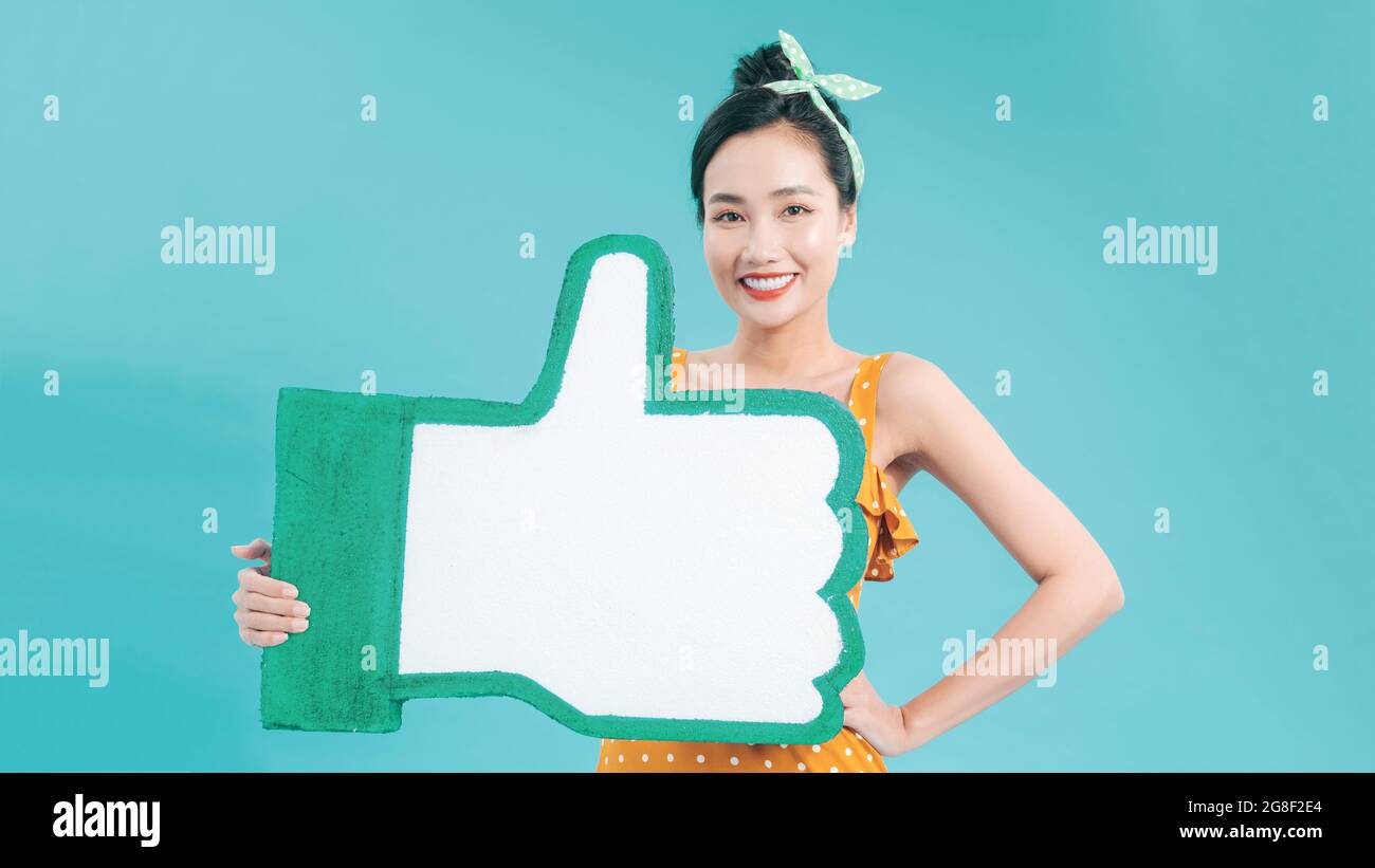 Portrait of attractive smiling girl holding at thumb up icon, holding social media like button, recommending forums and blogs Stock Photo