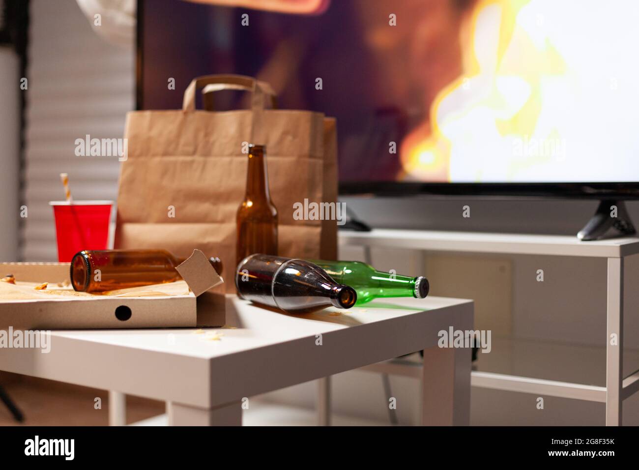 Close up of messy table with garbage food and booze leftover in empty unorganized dirty living room of depresive alone person. Untidy house apartment of woman with mental degenerating health Stock Photo