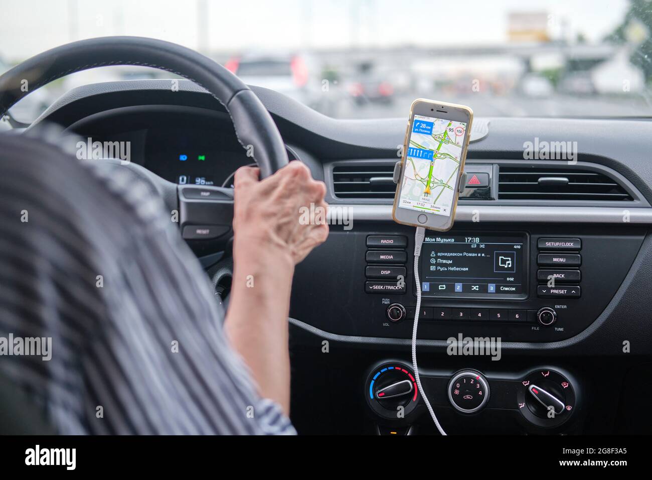 A woman drives a car using the navigator in a mobile iphone, yandex maps - Moscow, Russia, June 27, 2021 Stock Photo