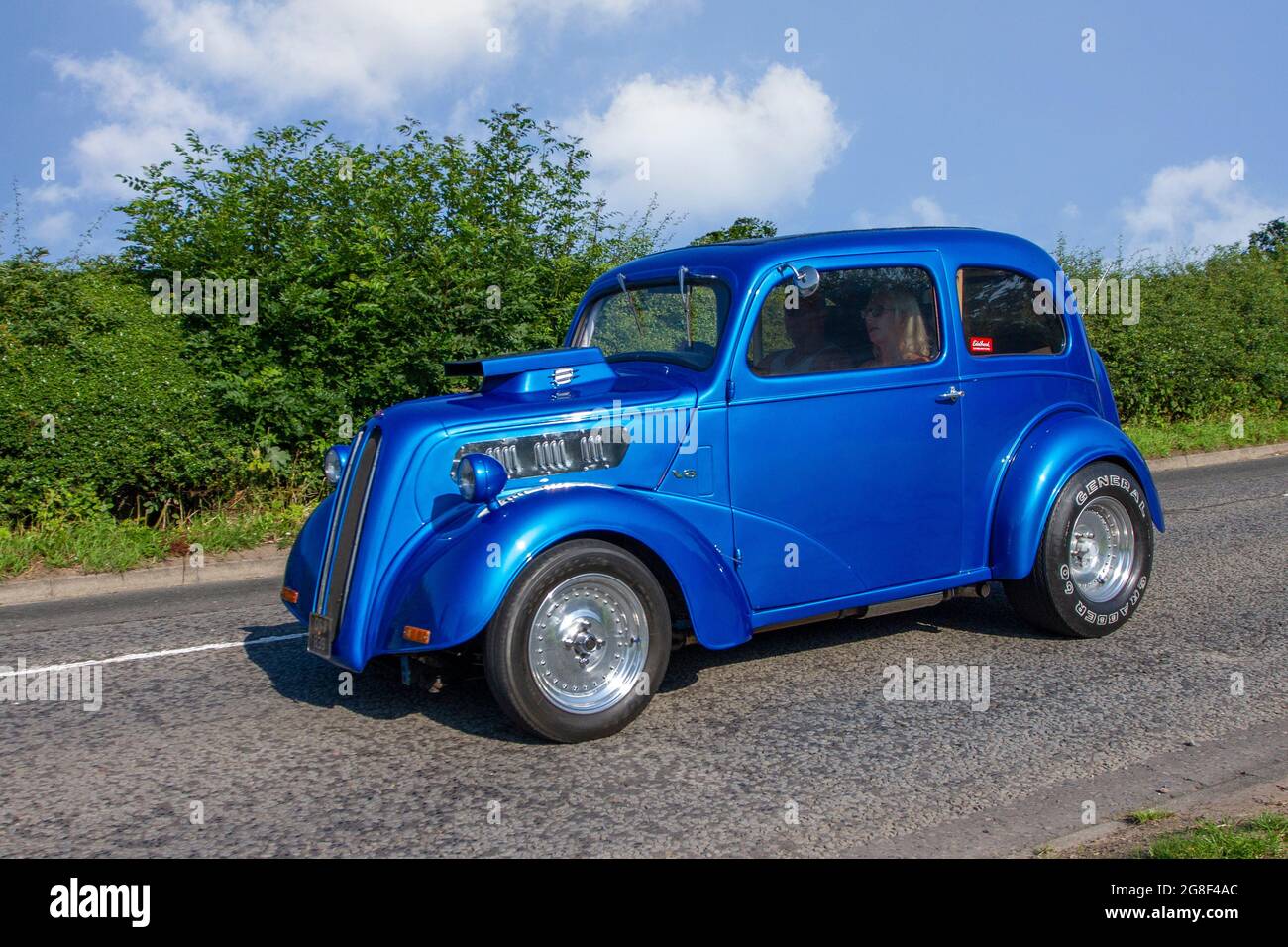1960 60s blue modified Ford Anglia V8 custom car en-route to Capesthorne Hall classic July car show, Cheshire, UK Stock Photo