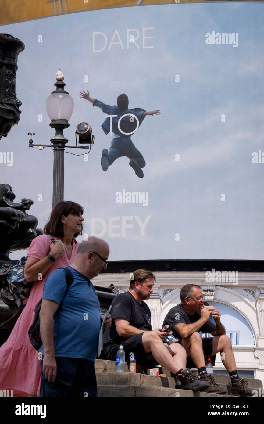 An image of a leaping figure from a Piccadilly Circus Calvin Klein ad whose  slogan is 'Dare to Defy', and resting Londoners on 'Freedom Day'. This date  is what Prime Minister Boris