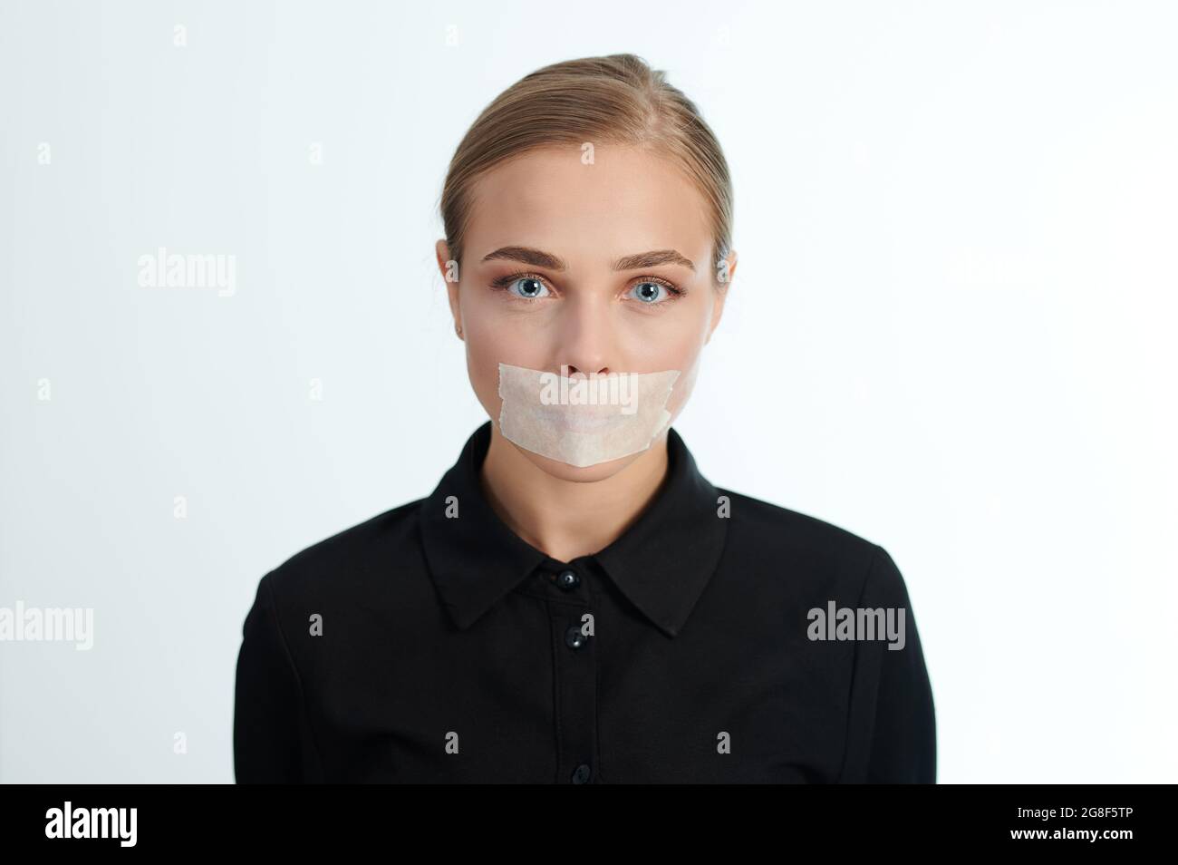 Portrait of sad woman with sealed mouth on white studio background. Violence theme Stock Photo