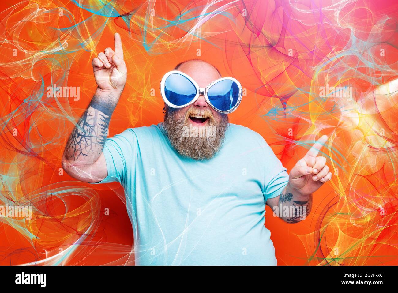 Fat happy man with beard, tattoos and sunglasses dances music Stock Photo