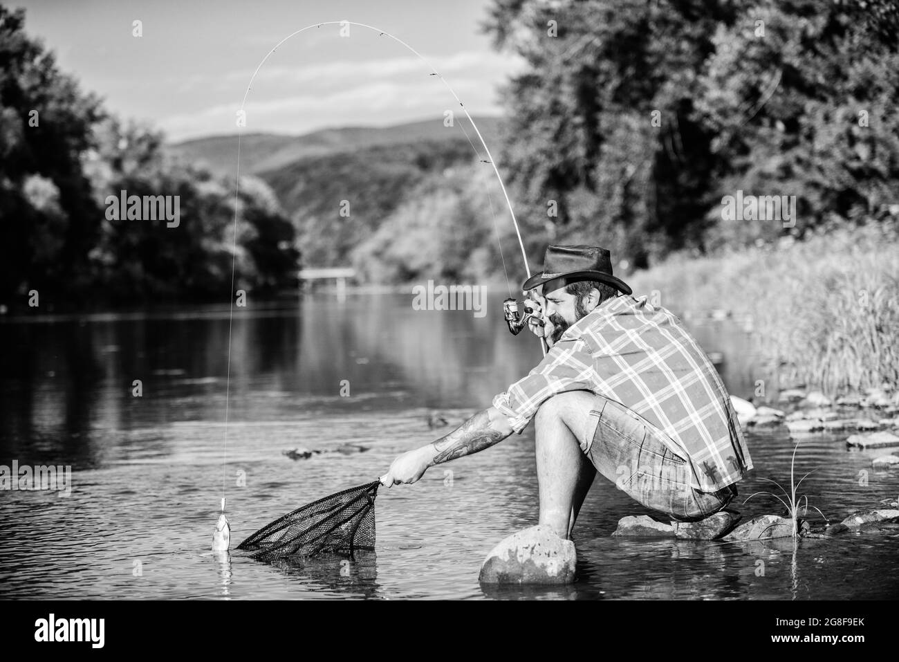 big game fishing. relax on nature. hipster fishing with spoon-bait. fly fish hobby of man. Hipster in checkered shirt. successful fisherman in lake Stock Photo