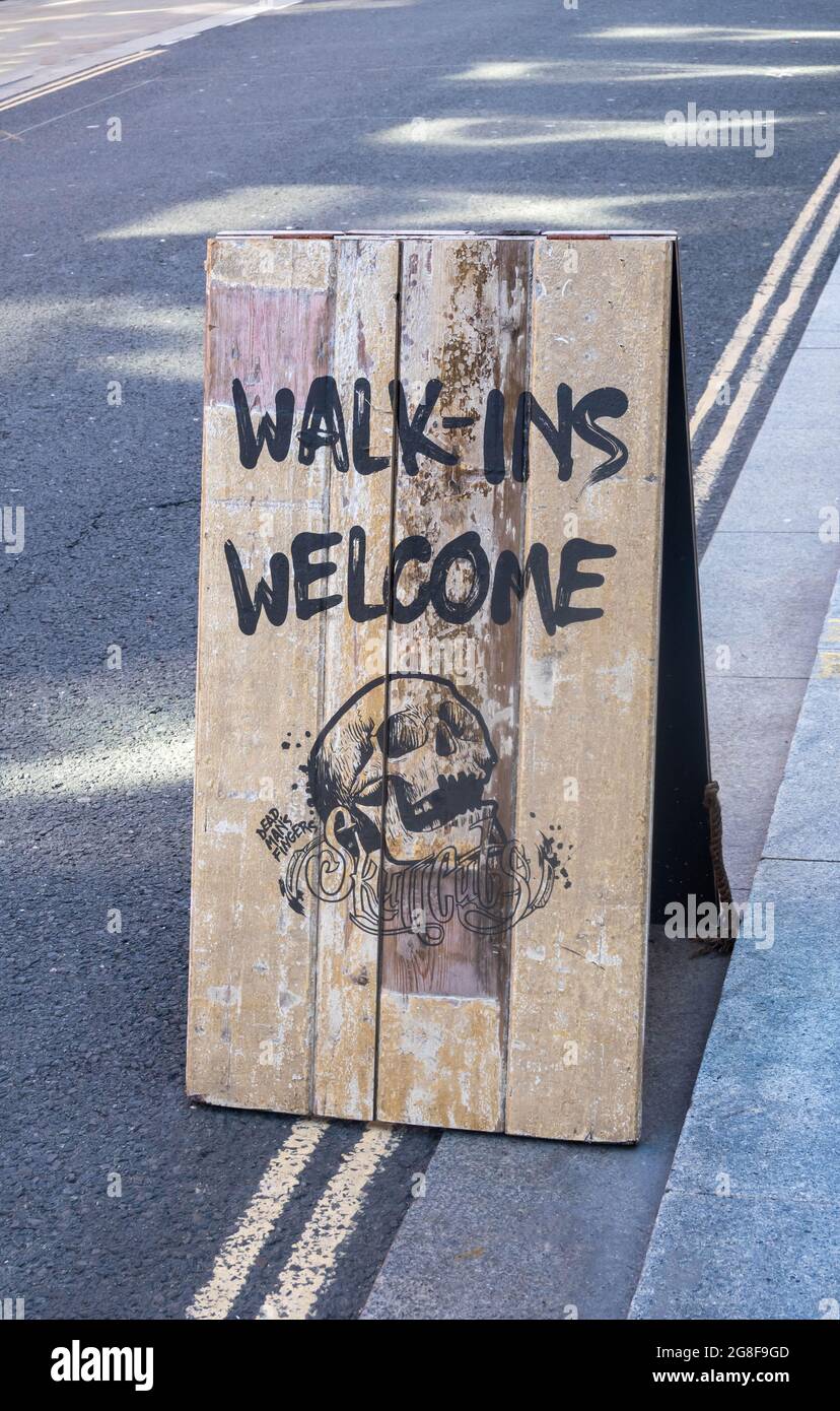 Wooden invitation street sign inviting walk-ins to Skullcuts barber and bar in Liverpool Stock Photo