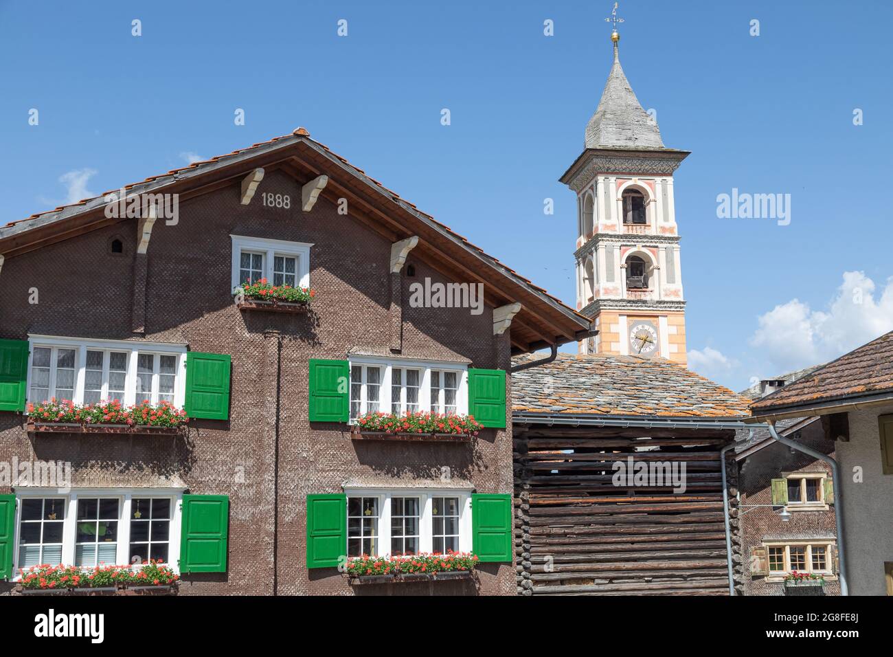 old wooden house next to the church tower of the mountain village Vrin in switzerland Stock Photo