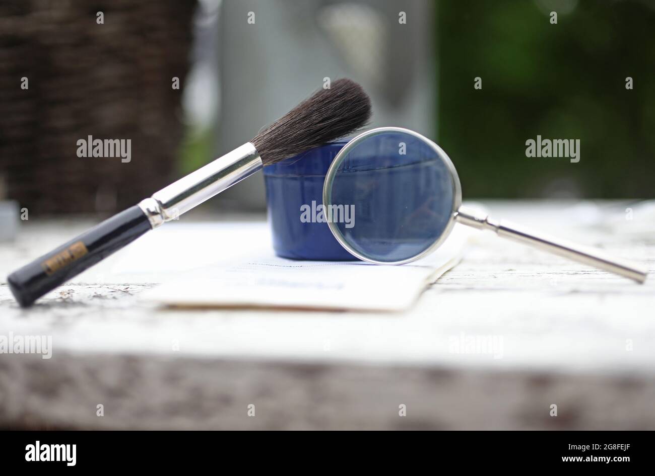 Fingerprint brush, black powder and a magnifying glass which is part of