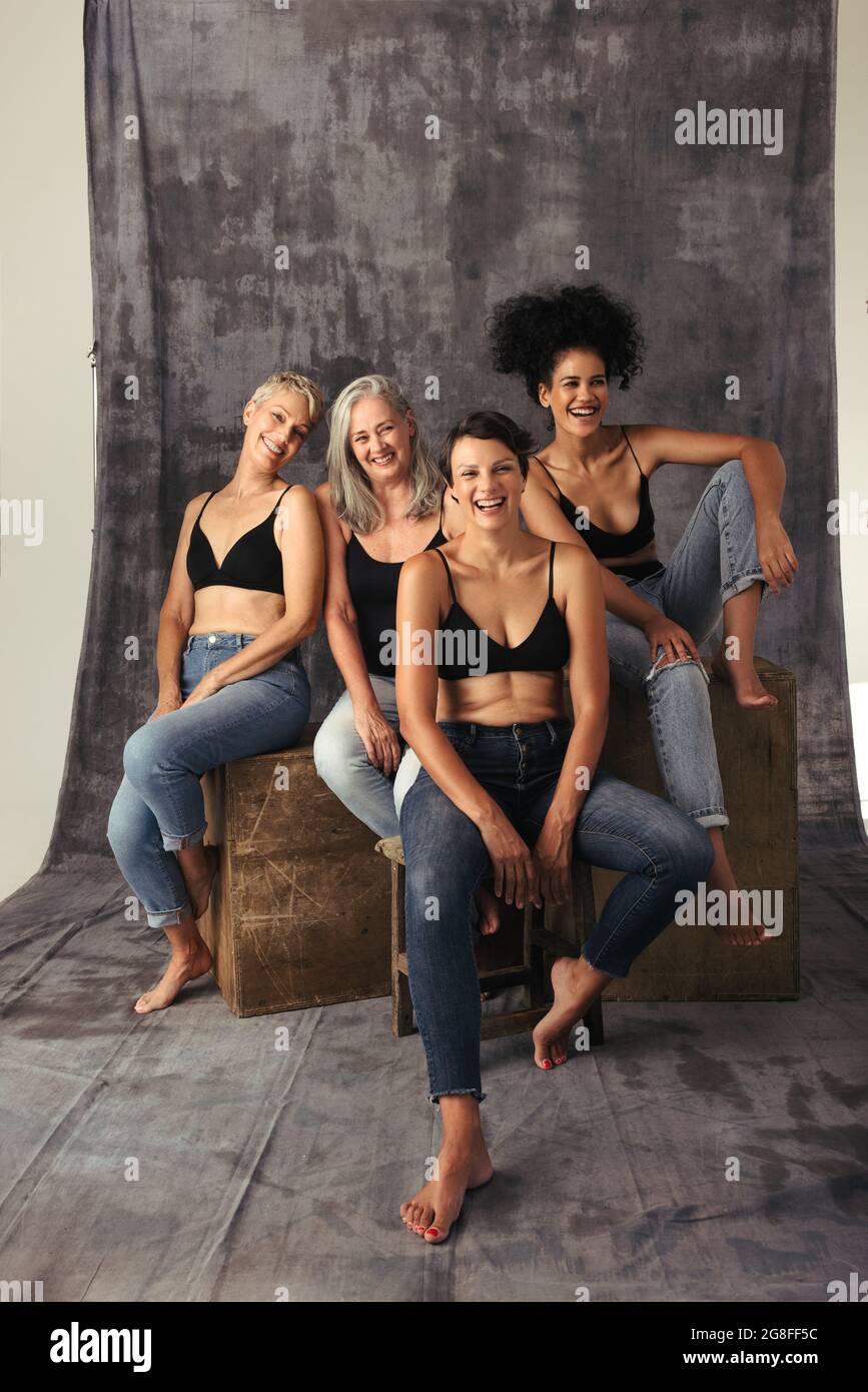 Full length shot of diverse women laughing together in a studio. Four body positive women of different ages celebrating their natural bodies while wea Stock Photo