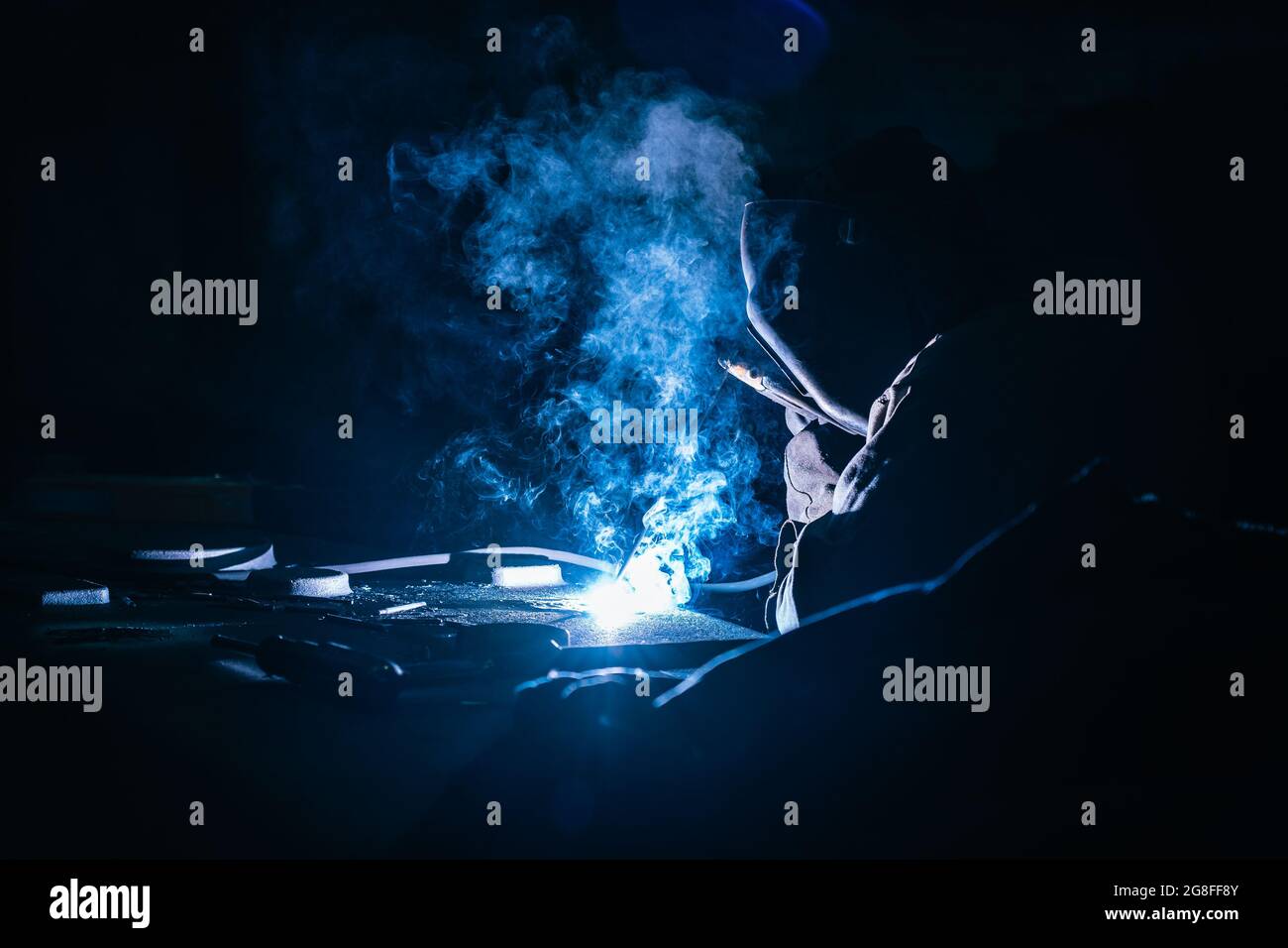 Welder at works close up. White flashes and welding smoke. Metalwork process. Stock Photo