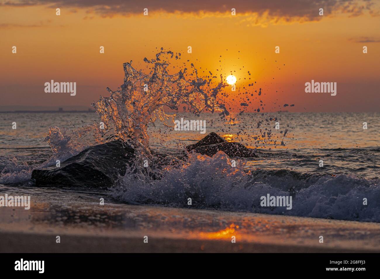 Beautiful view of splashing sea waves with the sunset in the background ...