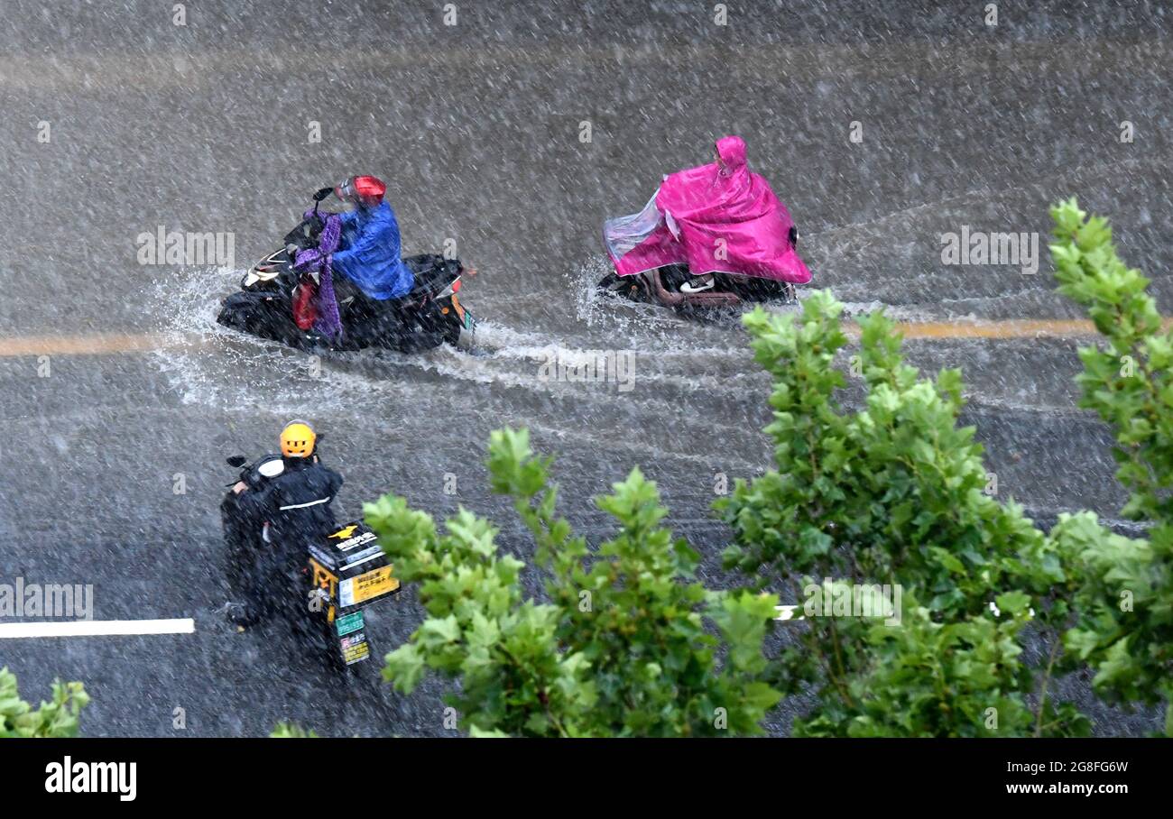 Zhengzhou, Henan, China. 20th July 2021.  People ride on a waterlogged road in Zhengzhou, capital of central China's Henan Province, July 20, 2021. More than 144,660 residents have been affected by torrential rains in central China's Henan Province since July 16, and 10,152 have been relocated to safe places, the provincial flood control and drought relief headquarters said Tuesday. Credit: Xinhua/Alamy Live News Stock Photo