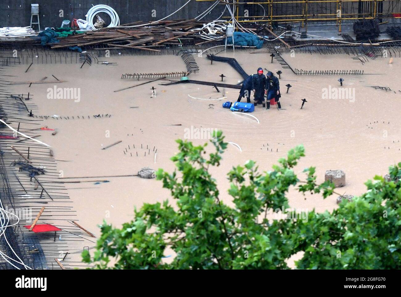 Zhengzhou, Henan, China. 20th July 2021.  Staff members drain away water at a construction site in Zhengzhou, capital of central China's Henan Province, July 20, 2021. More than 144,660 residents have been affected by torrential rains in central China's Henan Province since July 16, and 10,152 have been relocated to safe places, the provincial flood control and drought relief headquarters said Tuesday. Credit: Xinhua/Alamy Live News Stock Photo
