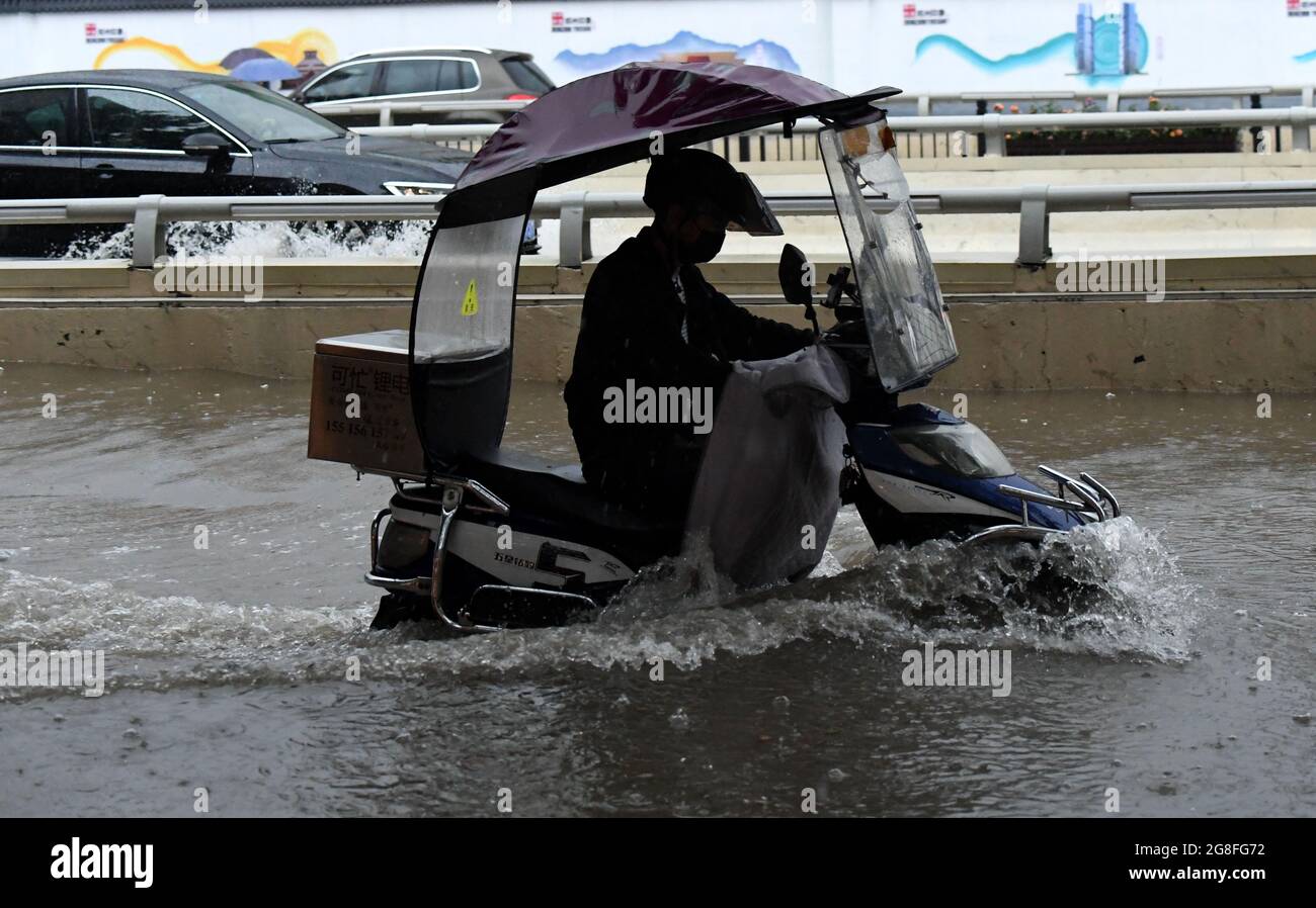 Zhengzhou, Henan, China. 20th July 2021. A man rides on a waterlogged road in Zhengzhou, capital of central China's Henan Province, July 20, 2021. More than 144,660 residents have been affected by torrential rains in central China's Henan Province since July 16, and 10,152 have been relocated to safe places, the provincial flood control and drought relief headquarters said Tuesday. Credit: Xinhua/Alamy Live News Stock Photo