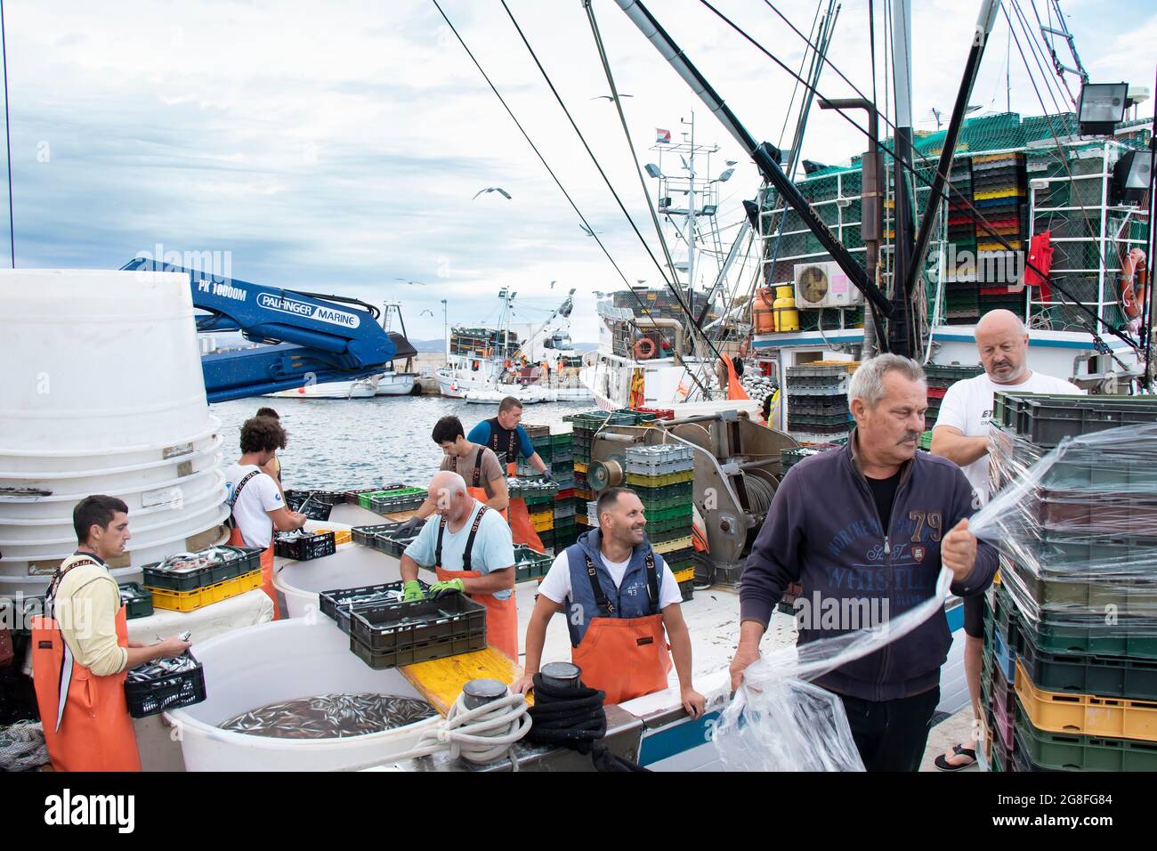 Tribunj, Croatia - July 4, 2021: Fishermen sorting out the catch on a deck of a moored commercial fishing boat Stock Photo