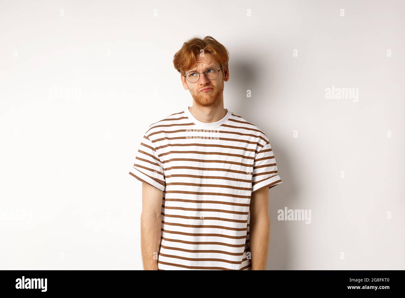 Sad and gloomy redhead man looking upper left corner, sulking and