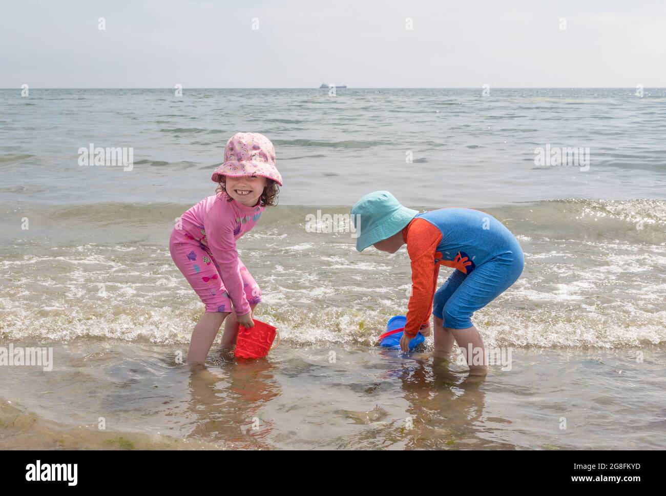 Fountainstown, Cork, Ireland. 20th July, 2021. As the heatwave continues, a brother and sister keep cool by playing in the water at Fountainstown Beach, Co. Cork, Ireland. - Picture; David Creedon / Alamy Live News Stock Photo