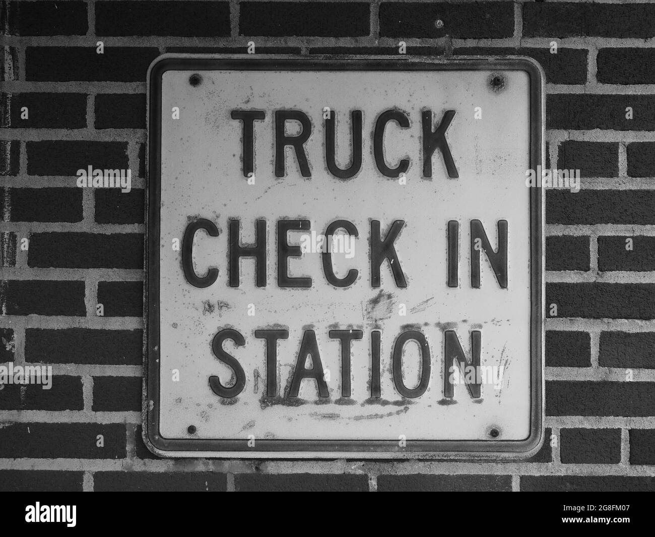 Monochromatic image of an iron plate with the text truck check in station engraved in it. Stock Photo