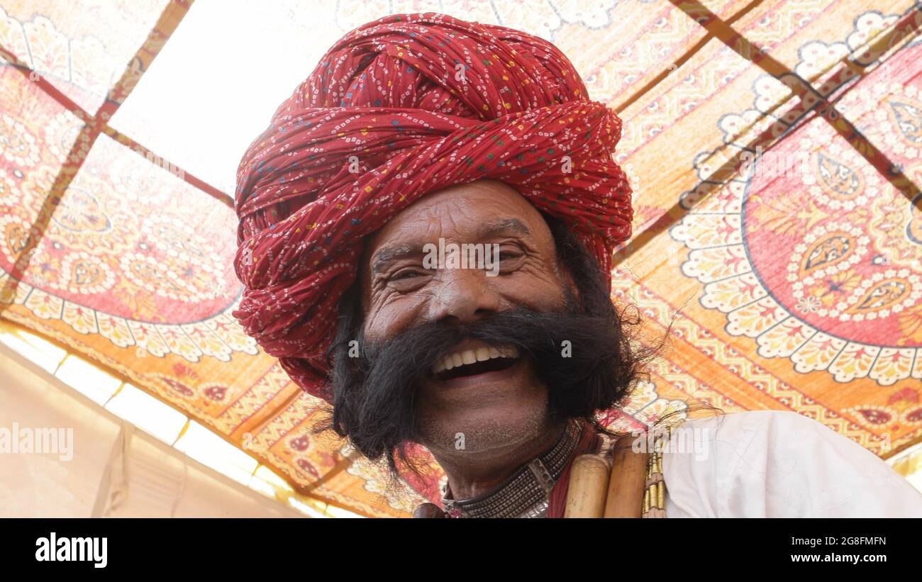 Low angle shot of a happy Indian man with a thick mustache and a pagri looking at the camera smiling Stock Photo