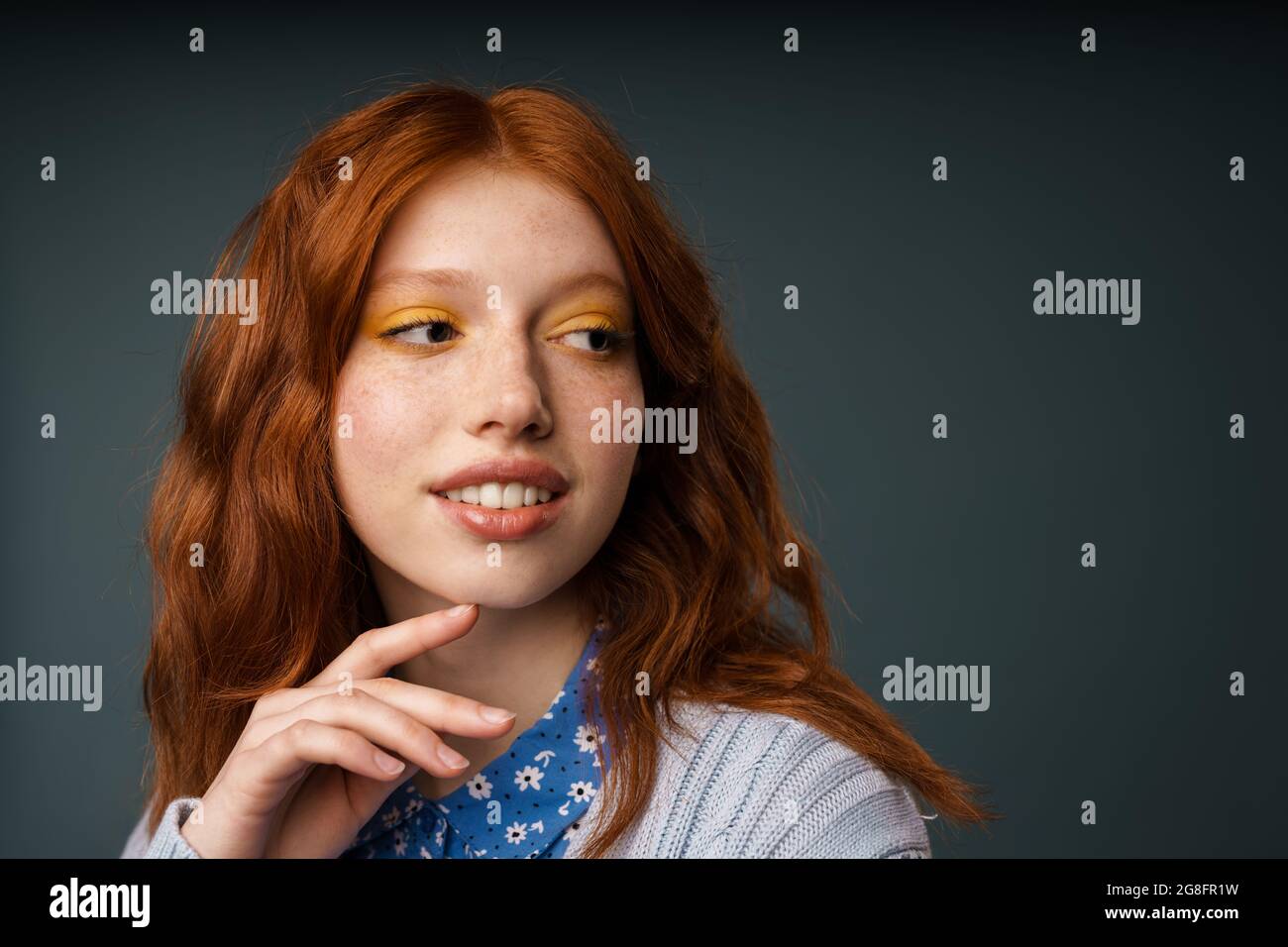Young ginger pleased woman posing and looking aside isolated over grey ...