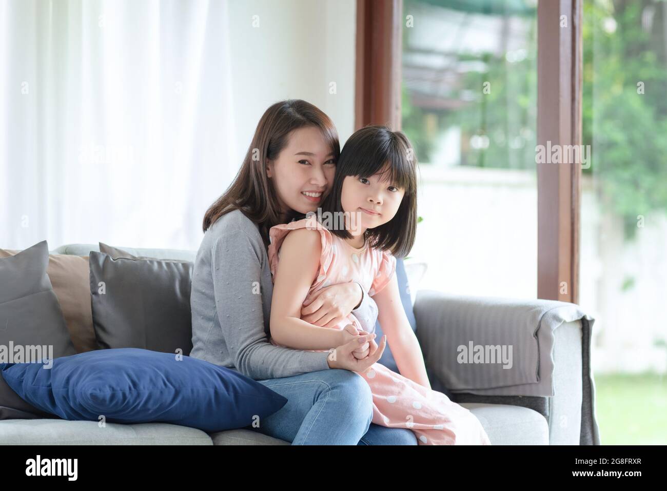 Asian mother feel hapiness during hug her cute daughter with love and care at home Stock Photo