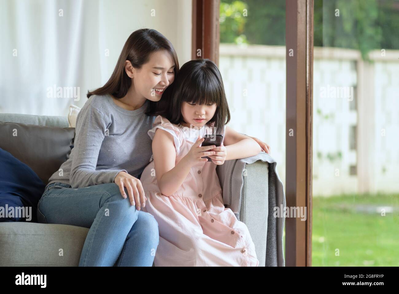 Asian mother and her daughter enjoy using internet via smart phone at home Stock Photo