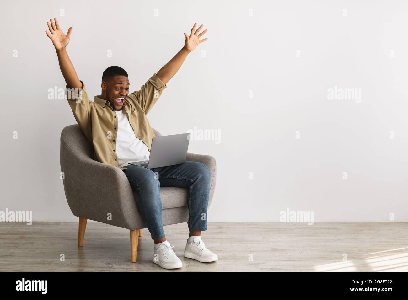 African Guy With Laptop Raising Hands In Joy, Gray Background Stock Photo