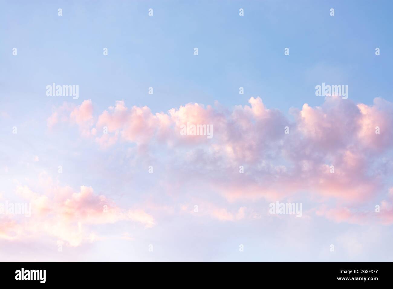 Pink and white fluffy clouds at sunset against a clear blue sky Stock ...