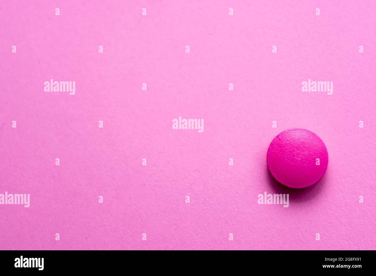 Pink pill on a pink table background closeup. Medical theme. Selective