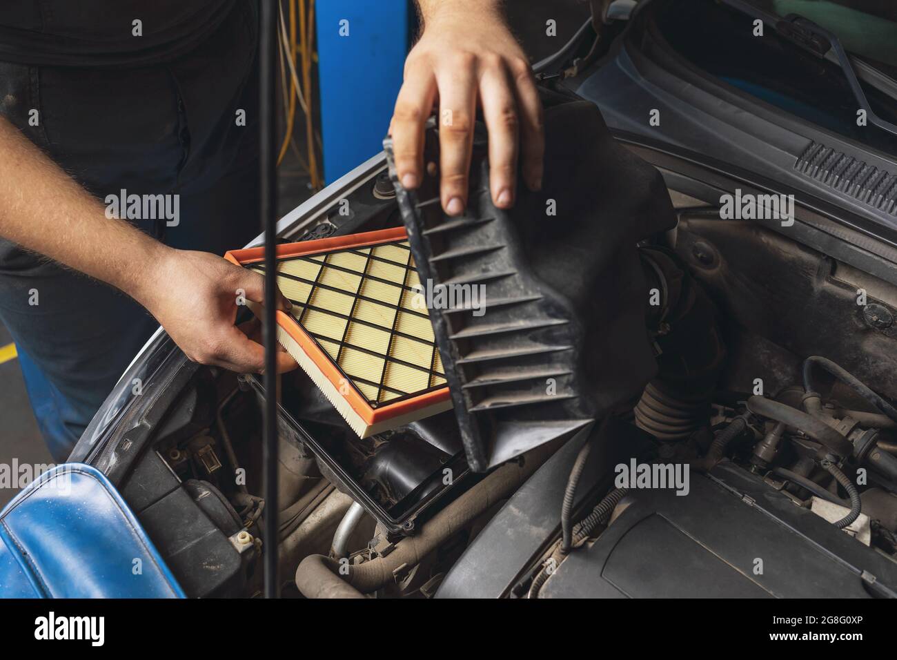 An auto mechanic installs a new engine air filter in the car Stock Photo
