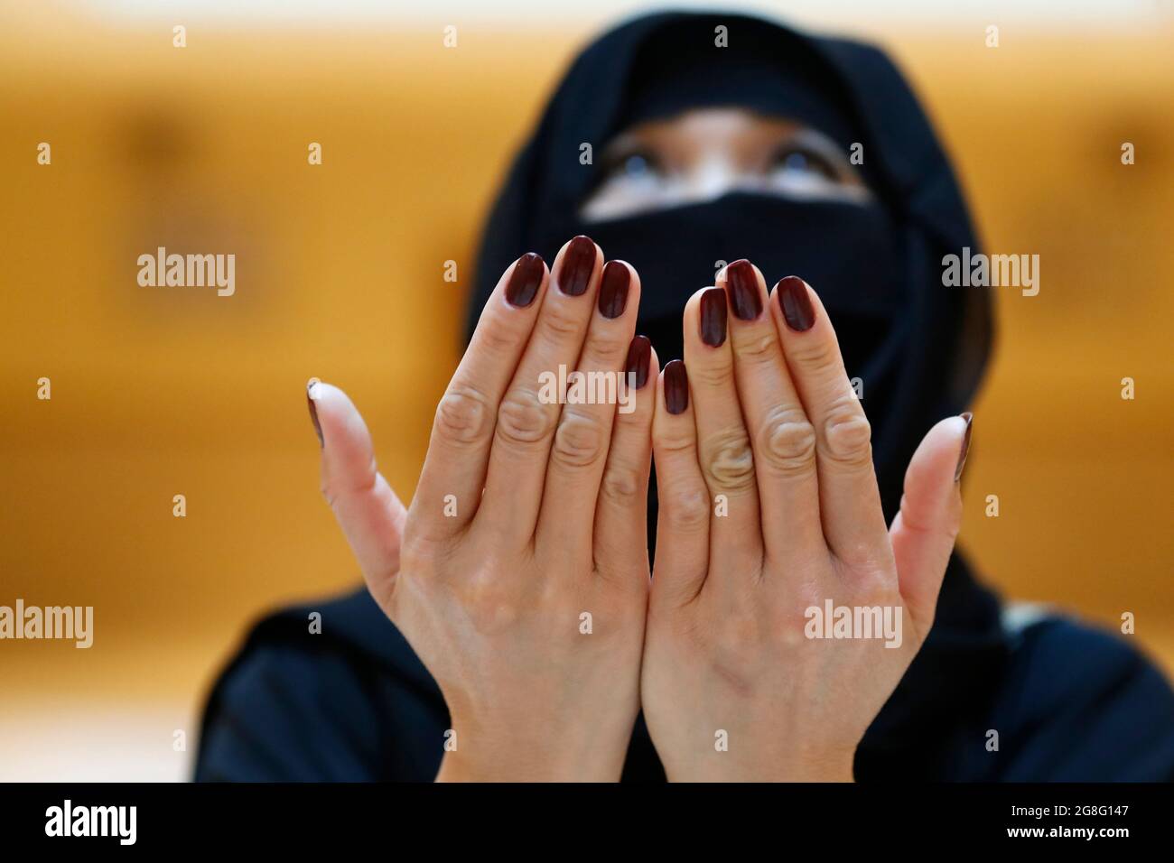 Muslim woman in abaya prays with her hands raised, United Arab Emirates, Middle East Stock Photo