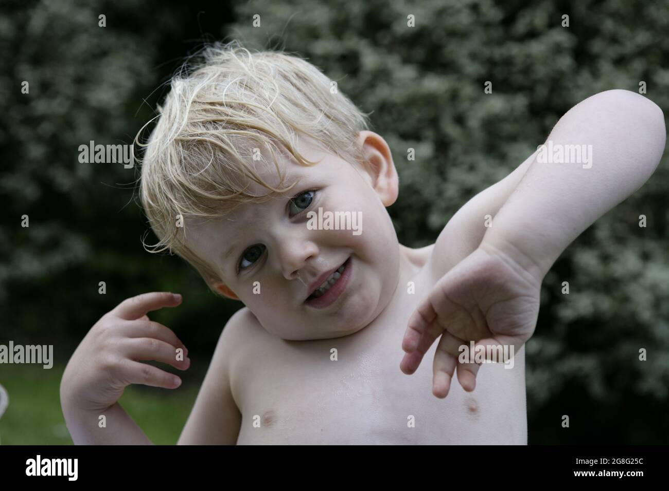 Outdoor summer garden play portrait of young naked toddler child with ...