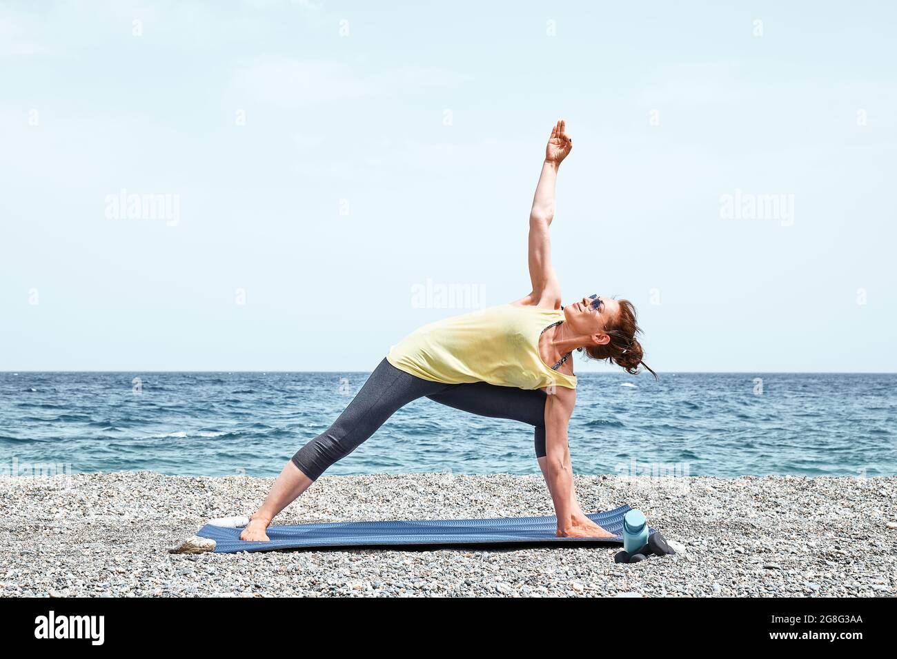 Woman doing Ashtanga Vinyasa yoga asana Parivrtta parsvakonasana - revolved  side angle pose on yoga mat on yoga mat in studio on grey bagckground Stock  Photo - Alamy