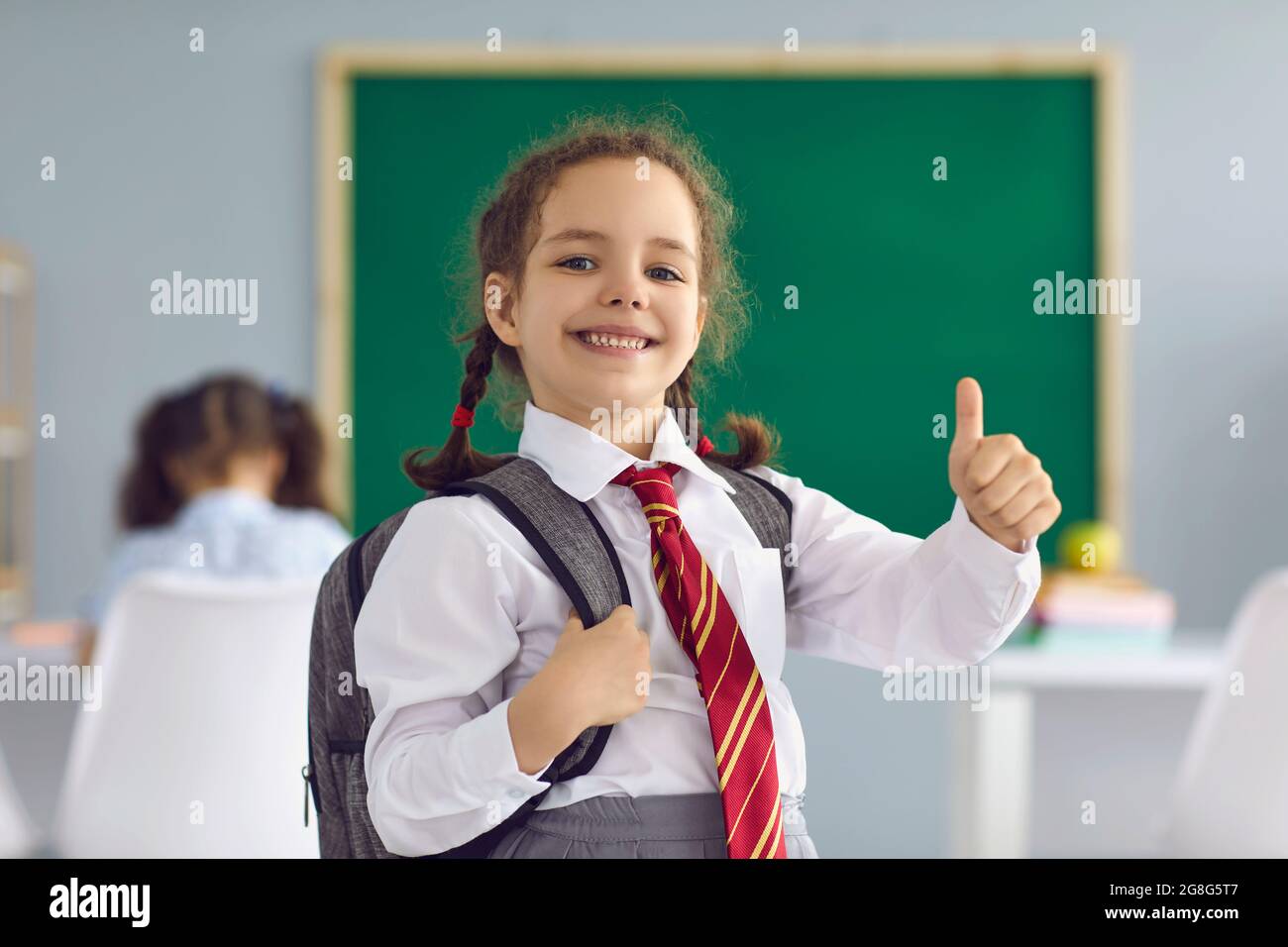 Back school. Happy schoolgirl raised her finger up smiling on the ...