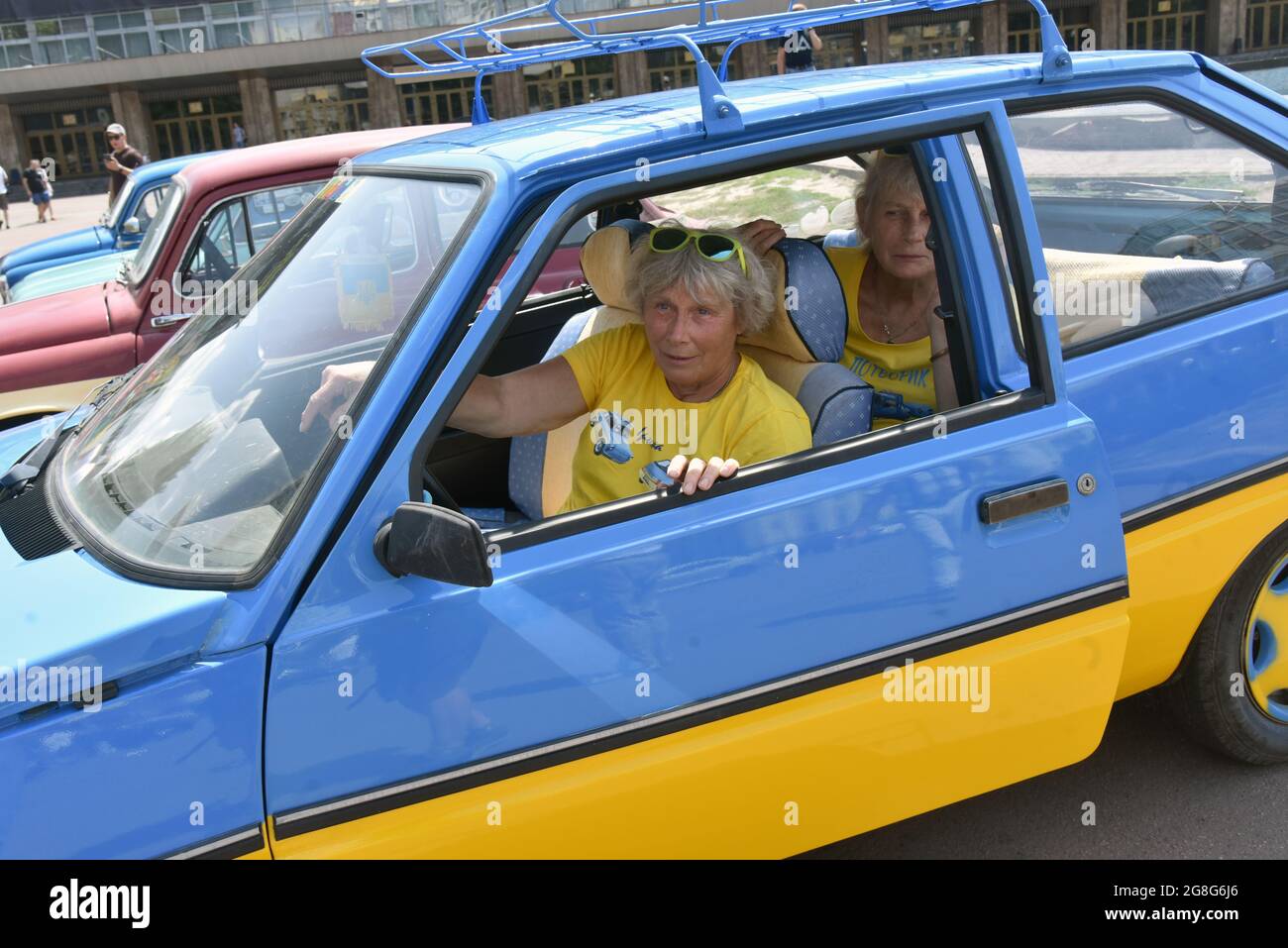 Non Exclusive: KYIV, UKRAINE - JULY 17, 2021 - Women sit in a car featuring the national colours of Ukraine during the show of the 1960-1994 ZAZ cars Stock Photo