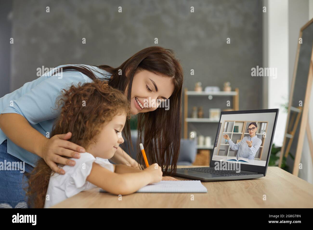 Mother and child learning online and having class with school teacher on their laptop Stock Photo