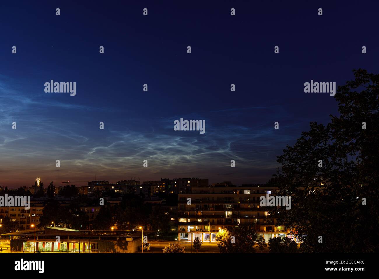 Noctilucent cloud (NLC, night clouds) over housing project and church in the evening. Cloud-like phenomena in mesosphere. They are highest clouds in E Stock Photo