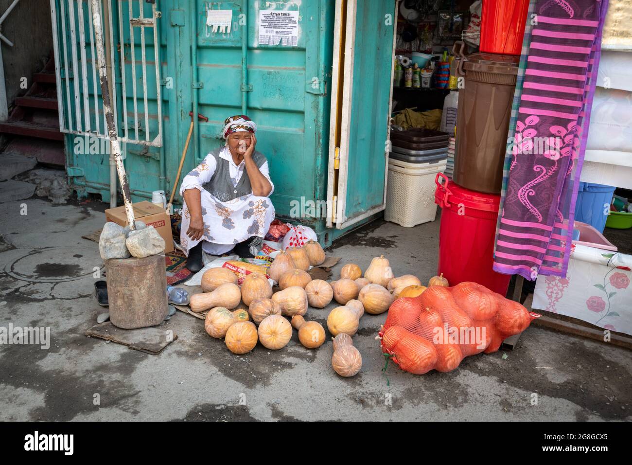 Osh, Kyrgyzstan - August 08, 2019: A senior Kyrgyz woman selling pumpkins  on the street at the Osh market. Stock Photo