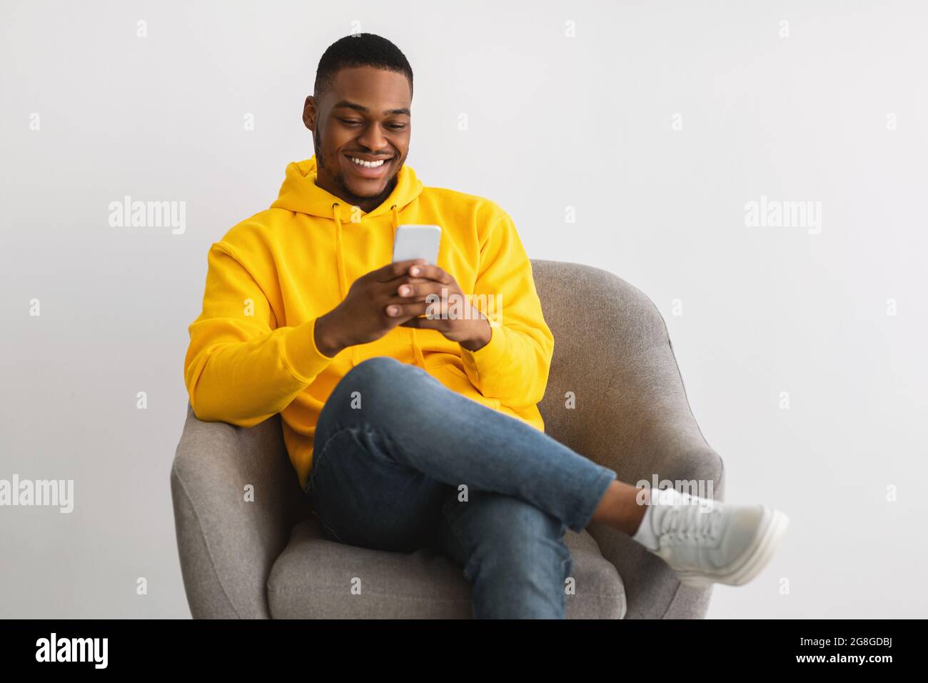 Happy Black Guy Using New Application On Smartphone, Gray Background Stock Photo