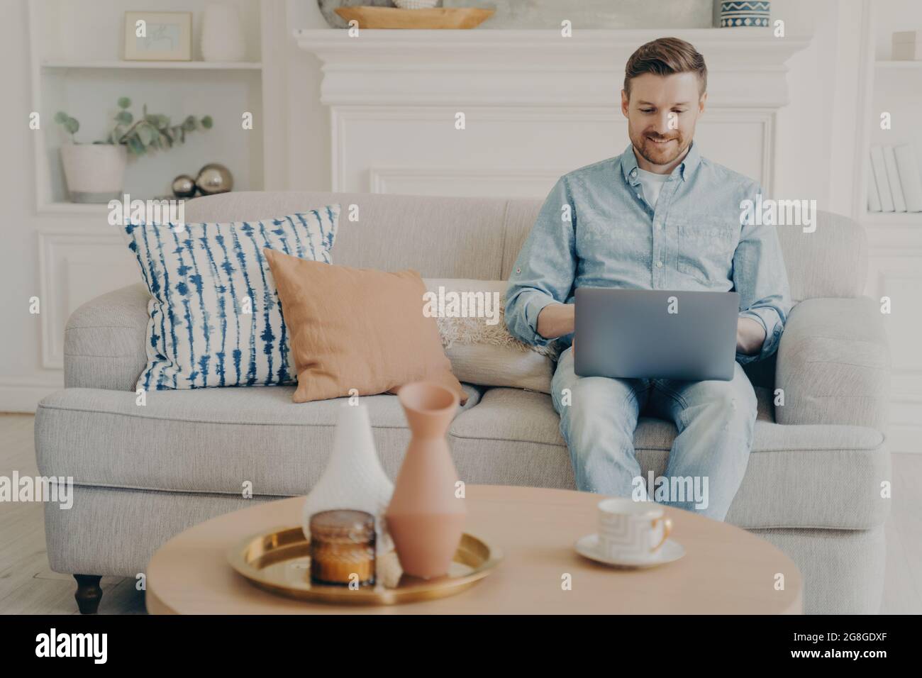 Young freelancer working on project using notebook on couch Stock Photo