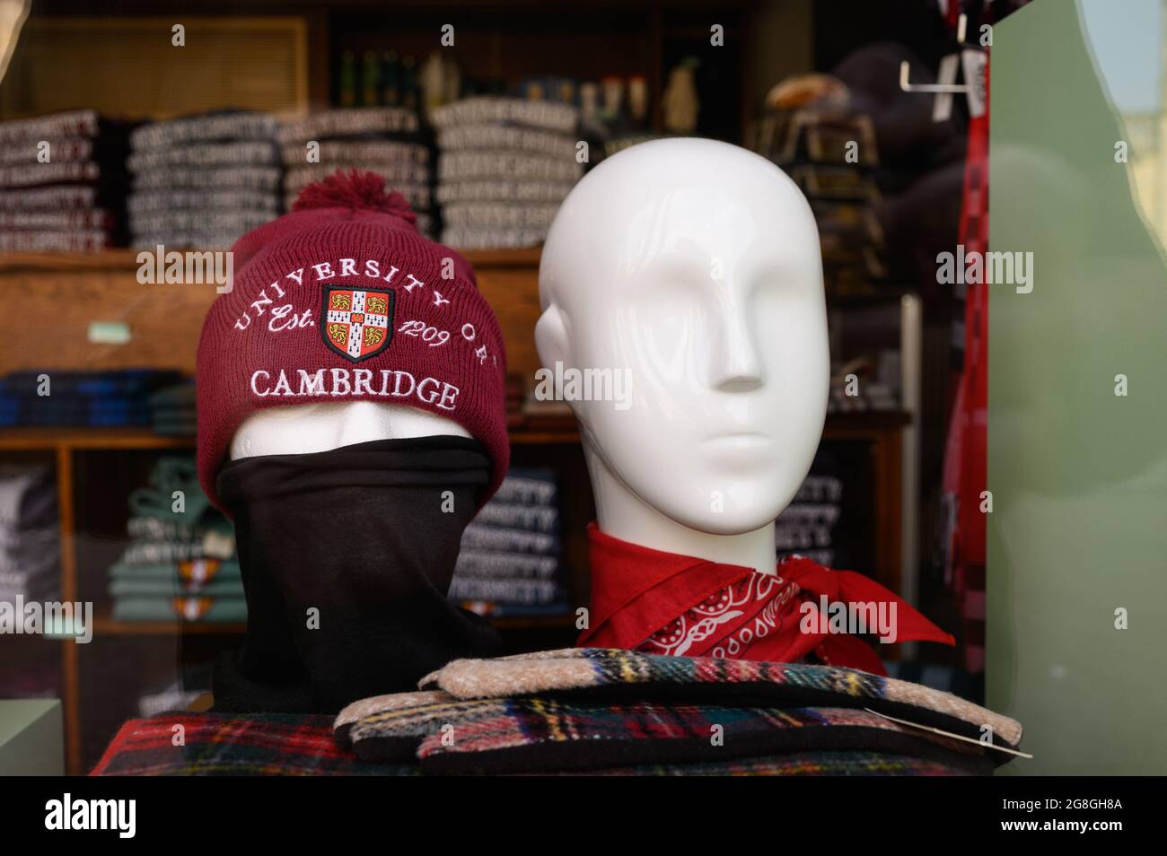 Two mannequin (dummy) heads in a shop window, one is wearing a beanie hat and mask, the other is not. Stock Photo