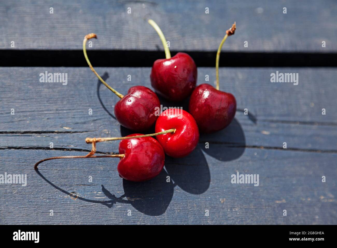 five red cherries on a wooden table Stock Photo