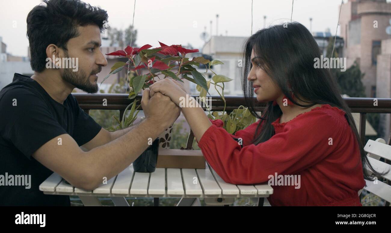 Young Indian couple sitting next to the table in the cafe and chatting