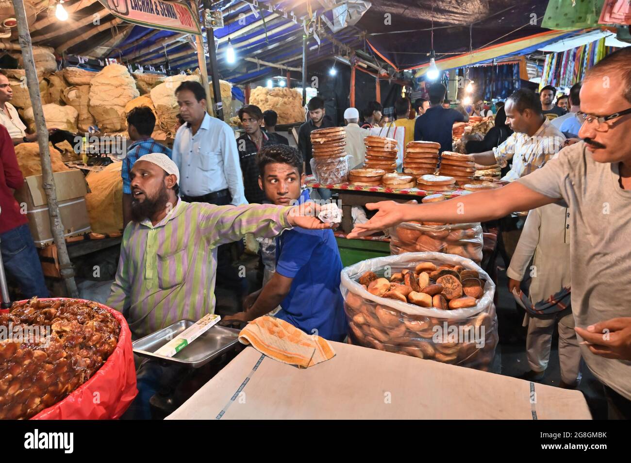 KOLKATA, WEST BENGAL, INDIA - MAY 27 2019 : Muslim seller exchaning money with buyer for selling Sevai, date fruit , biscuits and various sized fresh Stock Photo