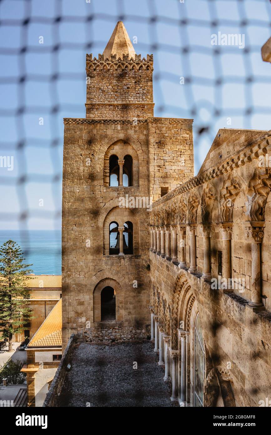 Cefalu,Sicily - June 6,2021.Roman Catholic cathedral.Famous UNESCO Heritage site in Italy.Facade of church with large Norman tower,view through blurre Stock Photo