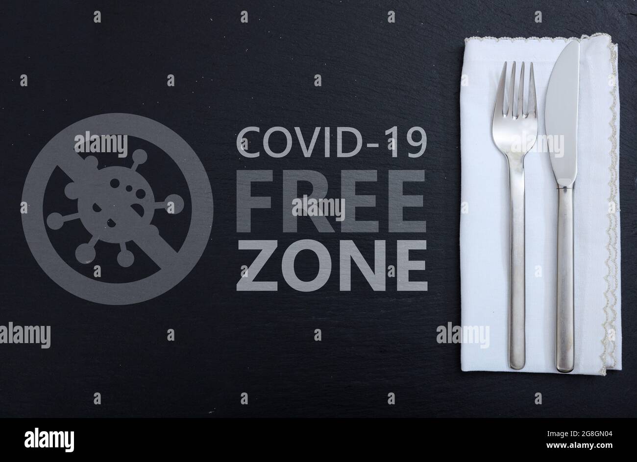 Covid free zone sign. COVID 19 FREE ZONE text label on dinner table setting background. Restaurant disinfected areas, vaccinated only concept Stock Photo