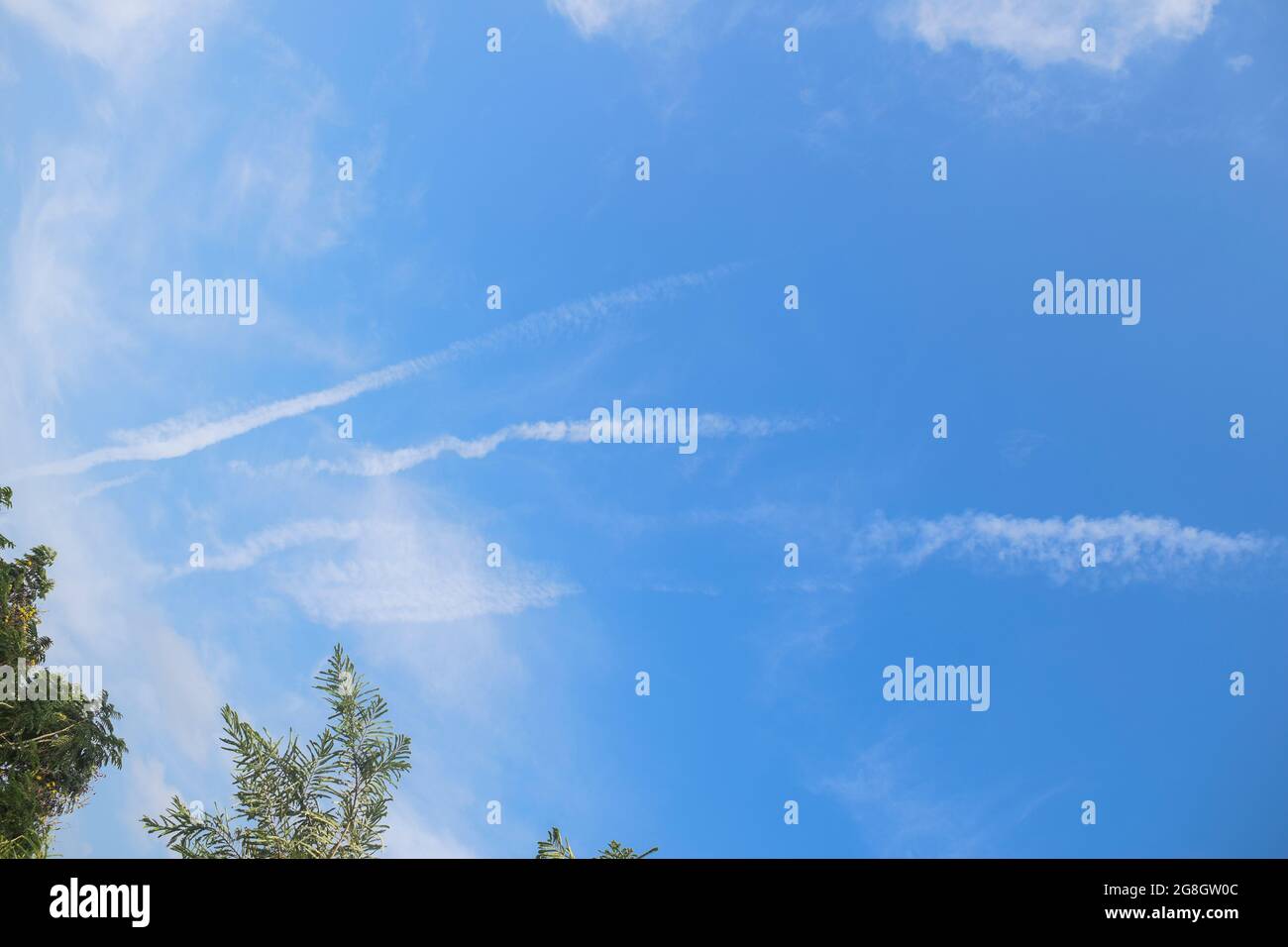 Jet plane contrails or air vapor smoke type trails seen in clear light blue sky from home. Jet plane in sky Stock Photo