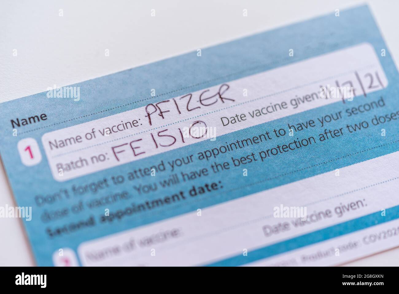 An NHS UK COVID-19 vaccination record card showing that the first PFIZER vaccine has been given, England, UK Stock Photo