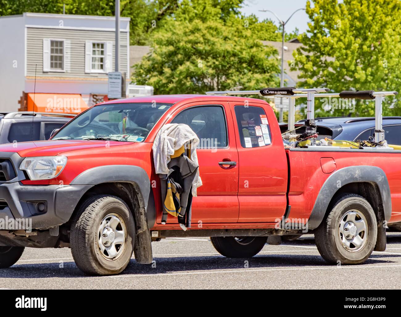 wet suit and towel hanging from a side view mirror on a Toyota Pickup truck in an East Hampton parking lot in East Hampton, NY Stock Photo