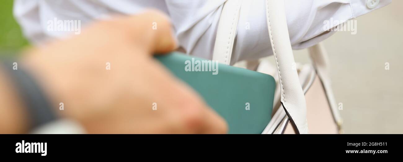 A man steals a wallet from a womans bag close up Stock Photo
