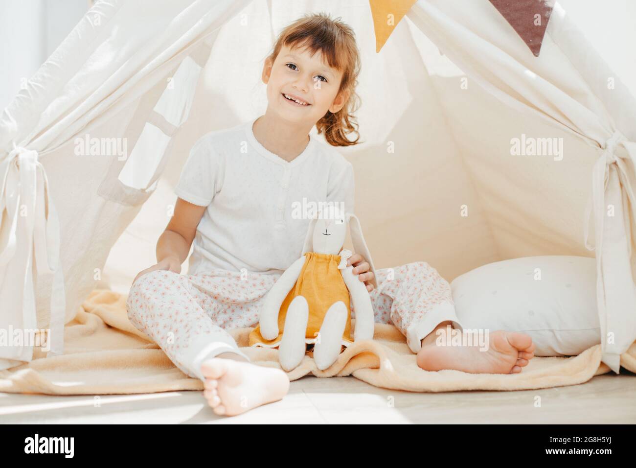 cute girl playing in teepee with fabric tilda bunny at home Stock Photo ...